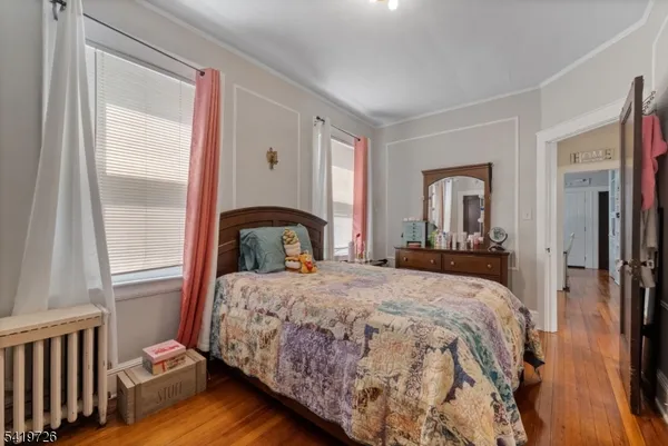 a bedroom with a bed and a large mirror next to a window