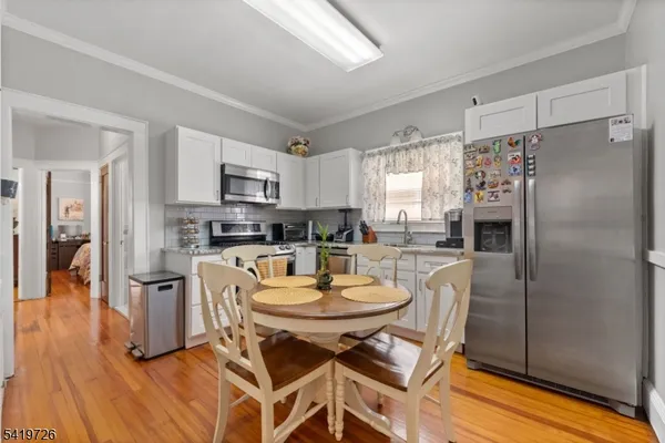 a kitchen with stainless steel appliances a refrigerator a stove a sink dishwasher and a dining table with wooden floor