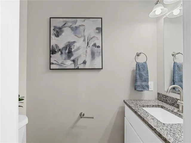 a bathroom with a granite countertop sink a mirror and vanity