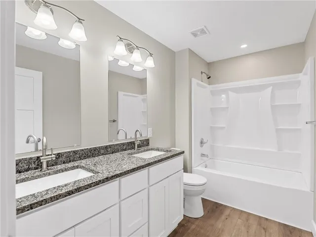 a bathroom with a granite countertop sink toilet a large mirror a bathtub and shower