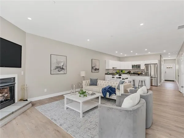 a living room with furniture a flat screen tv and kitchen view
