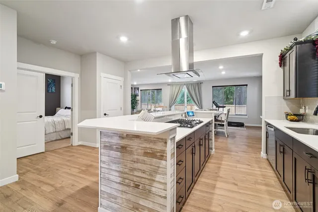 a kitchen with kitchen island a stove a sink a refrigerator and a dining table with wooden floor