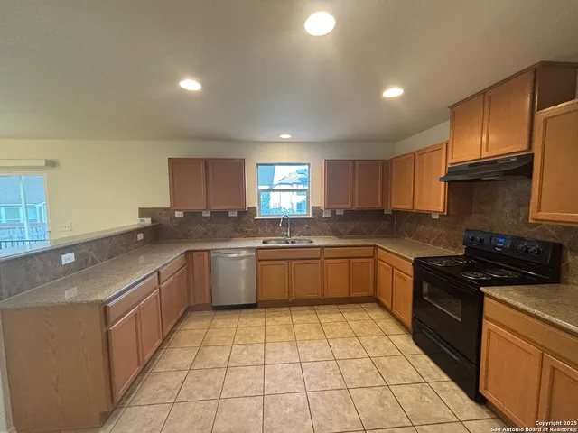 a large kitchen with a stove a sink dishwasher and a refrigerator