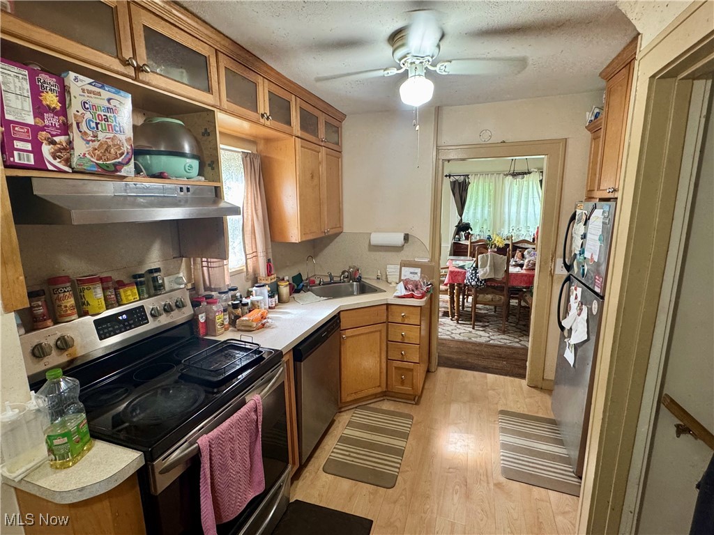 4406 Bayard Road Cleveland, OH 44121 - Photo 5 of 10 Kitchen with appliances with stainless steel finishes, under cabinet range hood, light countertops, light wood-style flooring, and brown cabinets