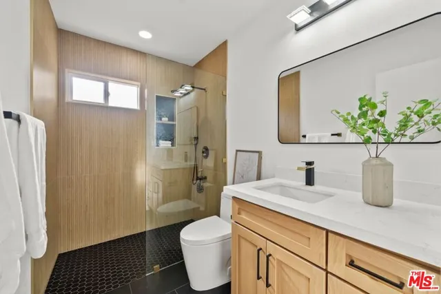 a bathroom with a granite countertop sink a toilet a mirror and shower