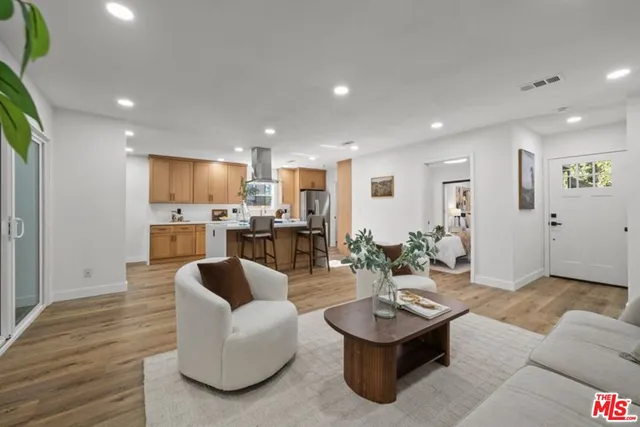 a living room with couches and kitchen view with wooden floor