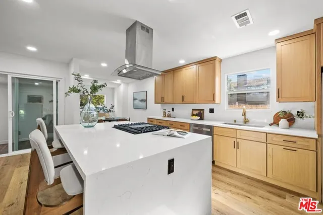 a kitchen with stainless steel appliances a sink stove and white cabinets with wooden floor