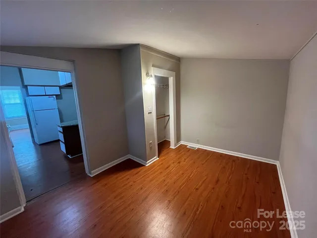 an empty room with wooden floor and entrance