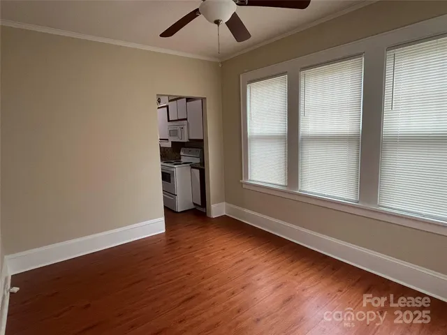 an empty room with wooden floor cabinet and windows