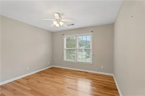 an empty room with wooden floor fan and windows