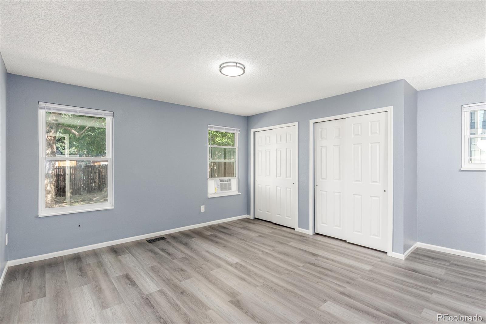 5105 Chandler Way Denver, CO 80239 - Photo 13 of 32 an empty room with wooden floor and windows