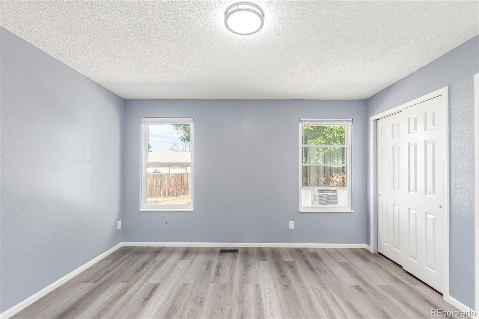 5105 Chandler Way Denver, CO 80239 - Photo 16 of 32 an empty room with wooden floor and windows