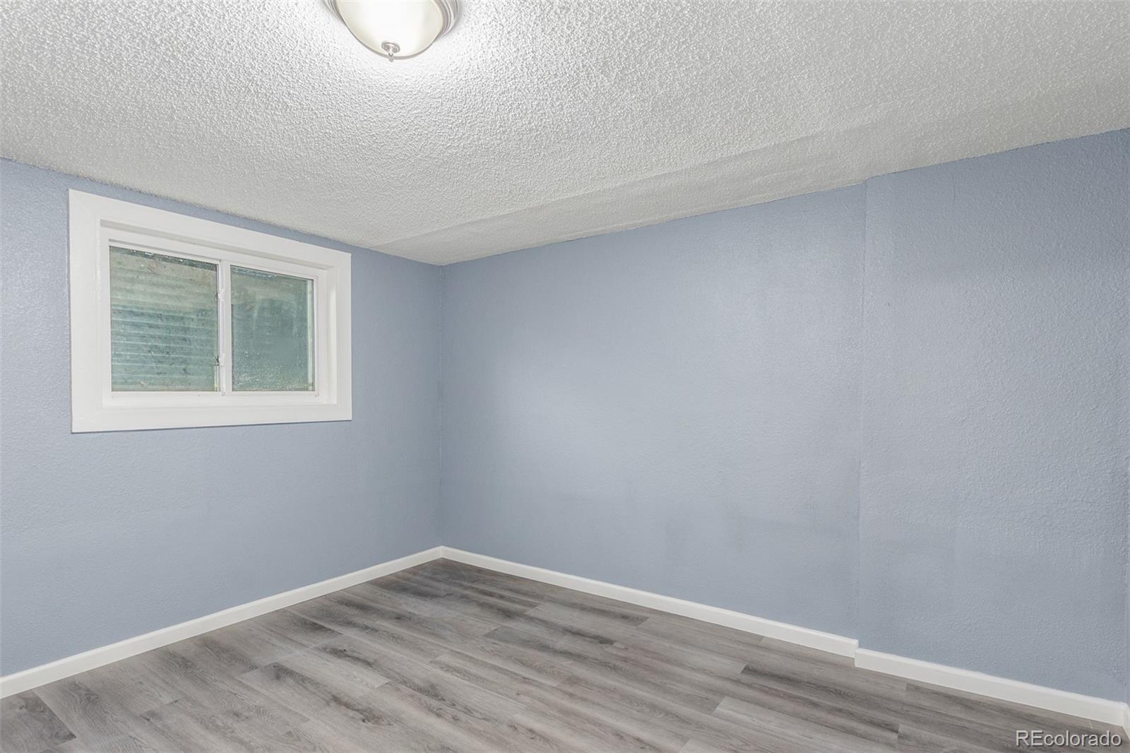 5105 Chandler Way Denver, CO 80239 - Photo 19 of 32 a view of an empty room with wooden floor and a window