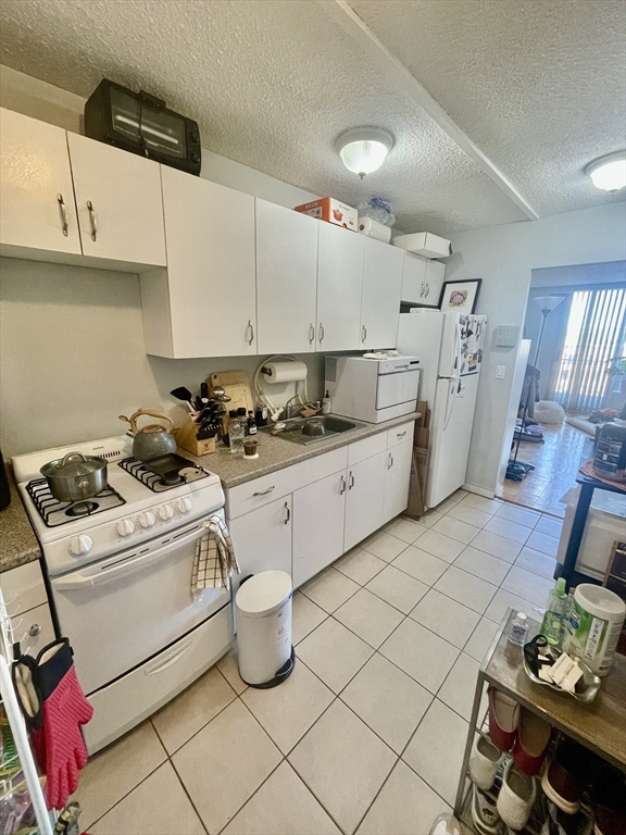 44 Washington Street, Unit 1009 Brookline, MA 02445 - Photo 5 of 12 a kitchen with sink a stove and cabinets