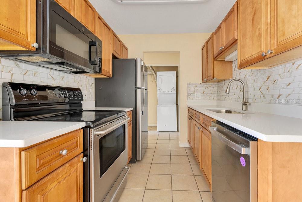 1695 Lee Road, Unit E103 Winter Park, FL 32789 - Photo 13 of 20 a kitchen with stainless steel appliances granite countertop a refrigerator a stove and a sink with wooden cabinets