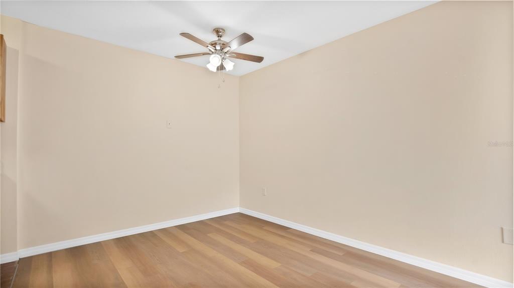 1695 Lee Road, Unit E103 Winter Park, FL 32789 - Photo 6 of 20 an empty room with a chandelier fan and wooden floor