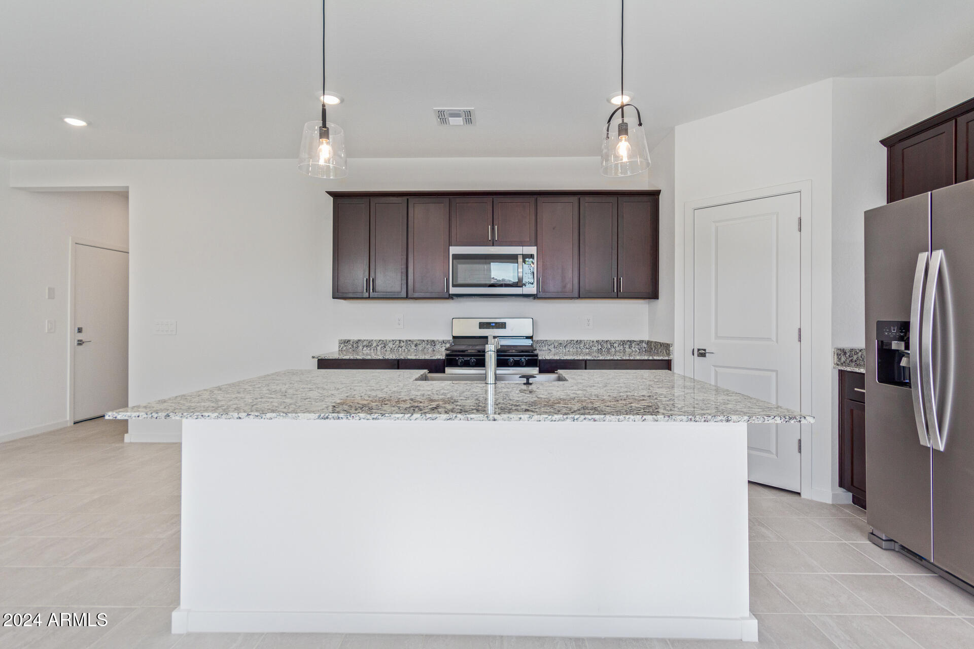 17629 West Madison Street Goodyear, AZ 85338 - Photo 8 of 46 a kitchen with stainless steel appliances granite countertop a sink a refrigerator and a granite counter tops