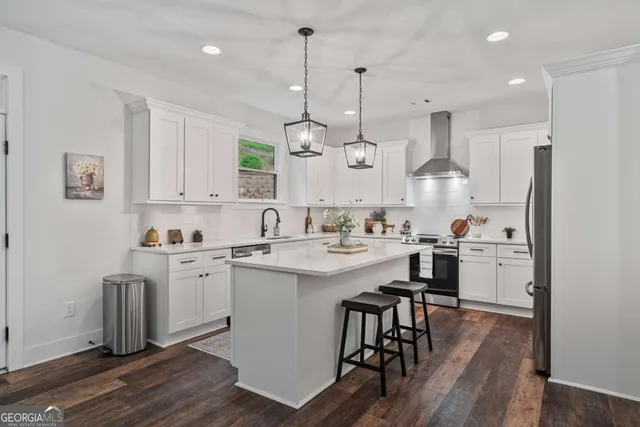 a kitchen with white cabinets stainless steel appliances and wooden floor