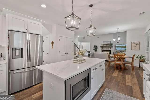 a kitchen with stainless steel appliances a stove a sink a refrigerator a center island a dining table and chairs