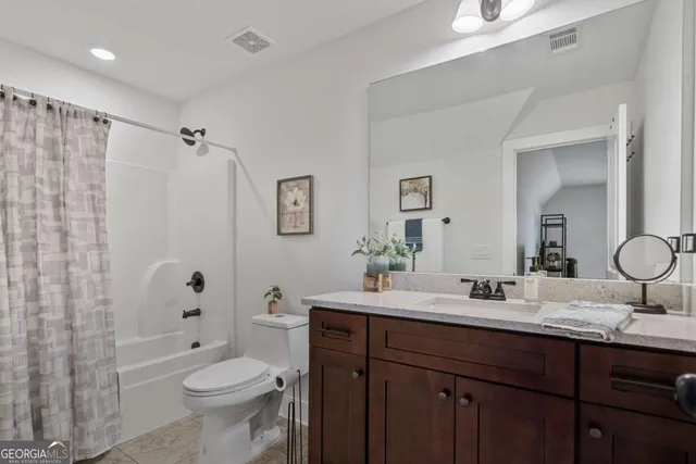 a bathroom with double vanity sink a toilet a shower and a mirror
