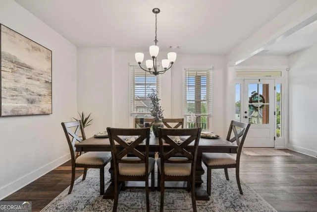 a dining room with wooden floor a chandelier a glass table and chairs