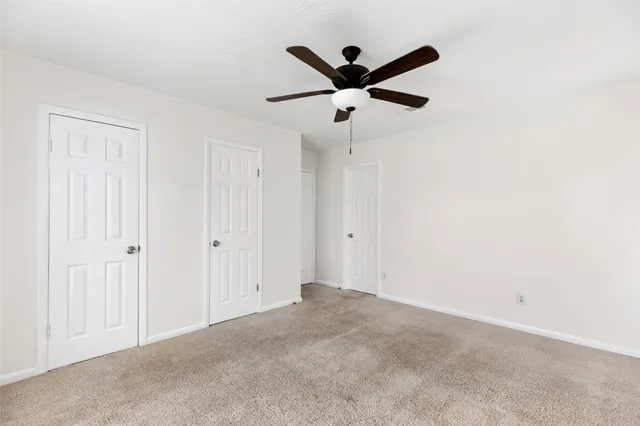an empty room with a ceiling fan and window
