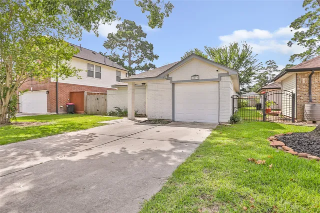 a view of a white house with a small yard and large tree