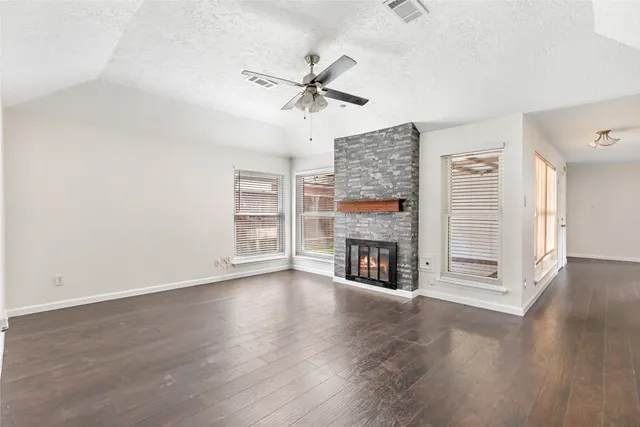 an empty room with wooden floor fireplace and windows