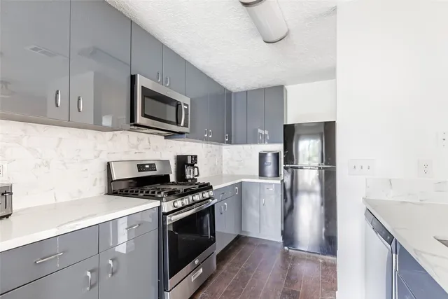 a kitchen with cabinets stainless steel appliances and wooden floor