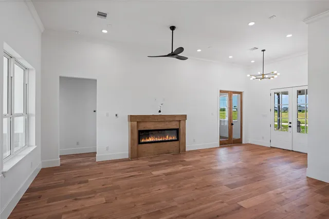 an empty room with wooden floor fireplace and window