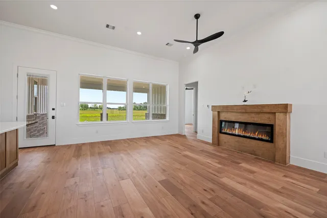 an empty room with wooden floor fireplace and windows