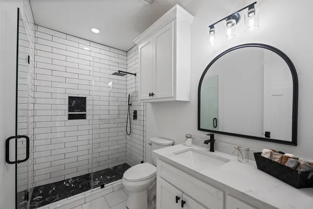 a bathroom with a granite countertop toilet sink and mirror