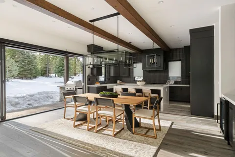 a dining room with stainless steel appliances kitchen island granite countertop a table chairs and a view of living room