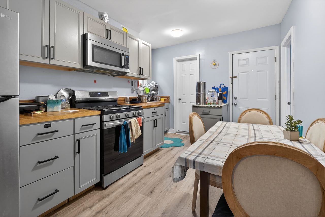 229 Patterson Street Harrison, NJ 07029 - Photo 12 of 26 a kitchen with stainless steel appliances granite countertop a stove top oven a sink dishwasher and white cabinets with wooden floor