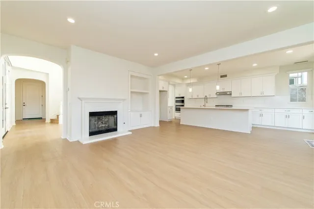 a kitchen with stainless steel appliances granite countertop a sink a oven a refrigerator and white cabinets with wooden floor