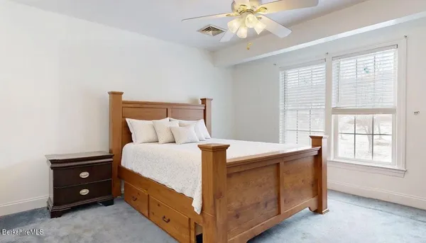 an empty room with chandelier fan and windows