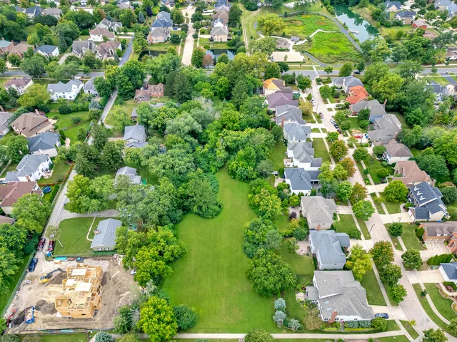 an aerial view of residential houses with outdoor space and trees all around