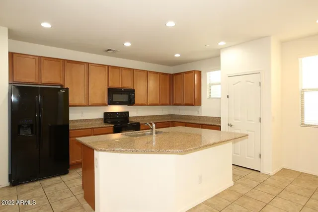 a kitchen with granite countertop a refrigerator a sink and wooden cabinets