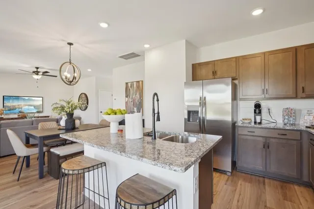 a kitchen with granite countertop a sink cabinetry a refrigerator and wooden floor