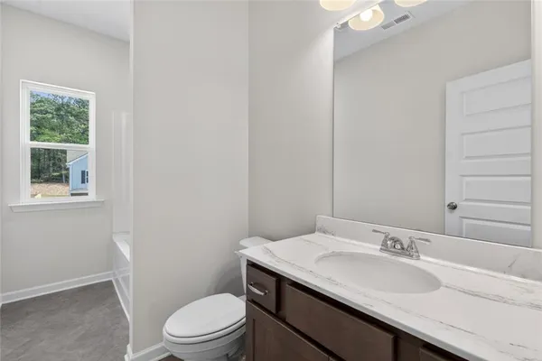 a bathroom with a granite countertop sink toilet a mirror and a window
