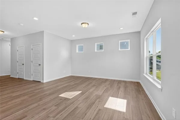 a view of an empty room with wooden floor and a window