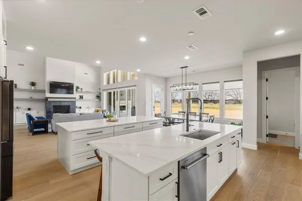 a large white kitchen with a large window and stainless steel appliances