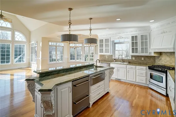 a kitchen with stainless steel appliances granite countertop a stove a sink and a wooden floors