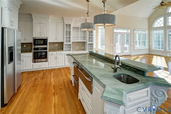 a kitchen with stainless steel appliances granite countertop a sink a stove and a wooden floors