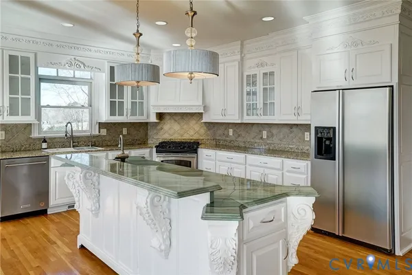 a kitchen with stainless steel appliances granite countertop a sink a stove a refrigerator a center island and a stove