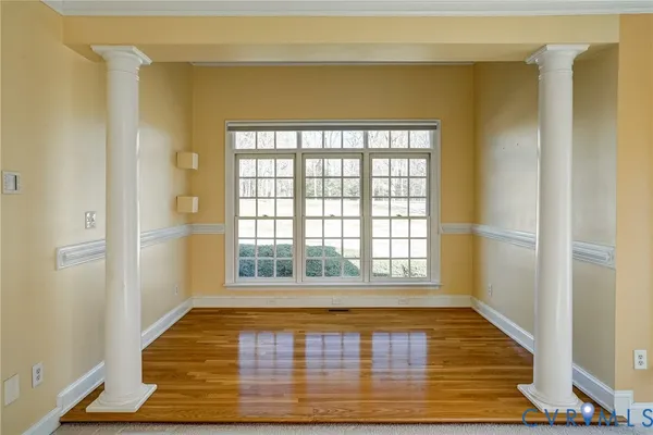 a view of an empty room with wooden floor and a window