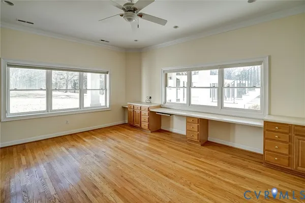 a view of empty room with wooden floor and fan