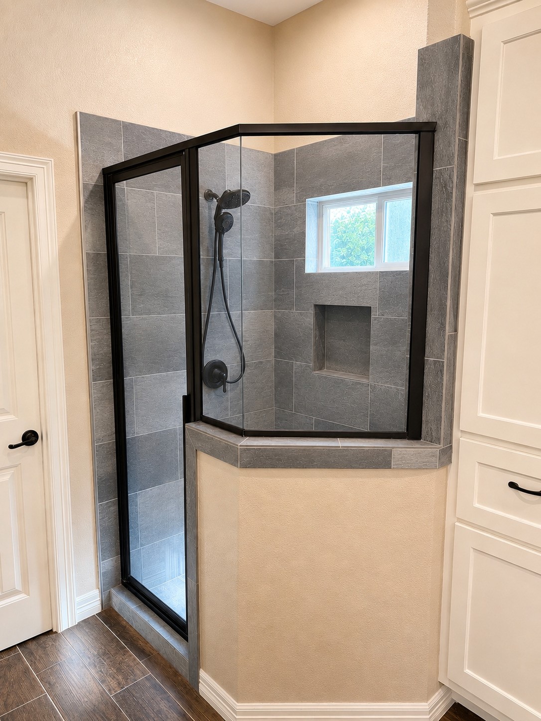 27656 Rio Blanco Drive Splendora, TX 77372 - Photo 11 of 18 This Primary Bathroom features a modern corner shower with sleek gray tiles and a black-framed glass door. It includes a built-in niche for storage and a window for natural light, creating a bright and functional space.