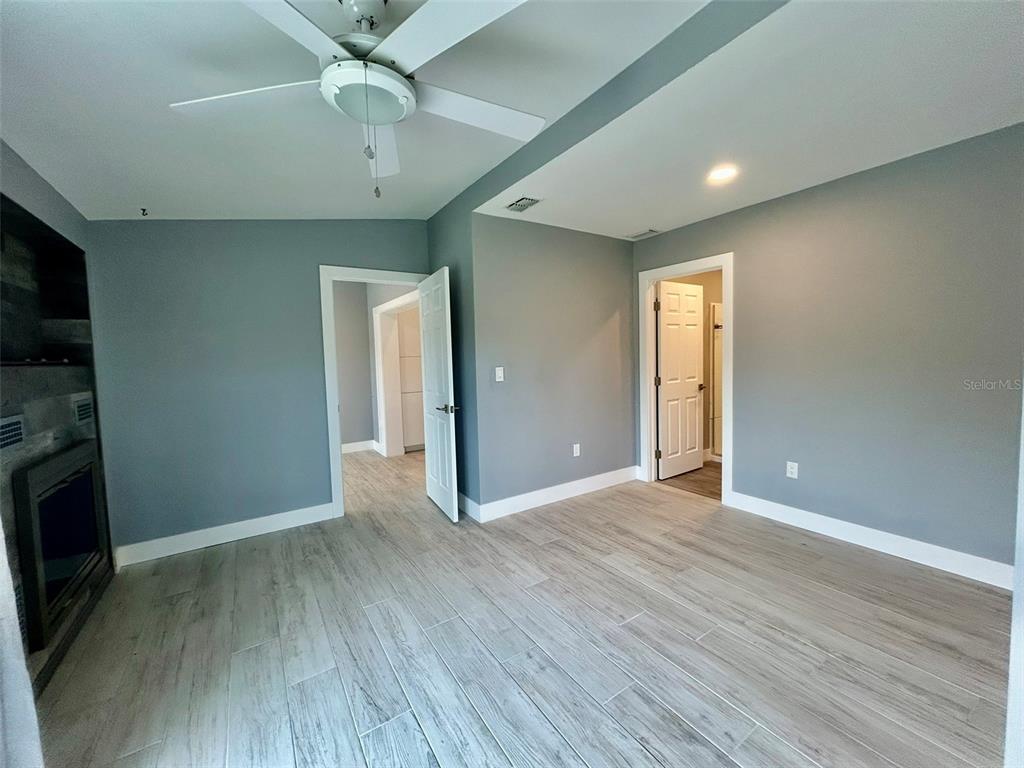 3112 Magnolia Way Punta Gorda, FL 33950 - Photo 12 of 20 an empty room with wooden floor a ceiling fan a fireplace and windows