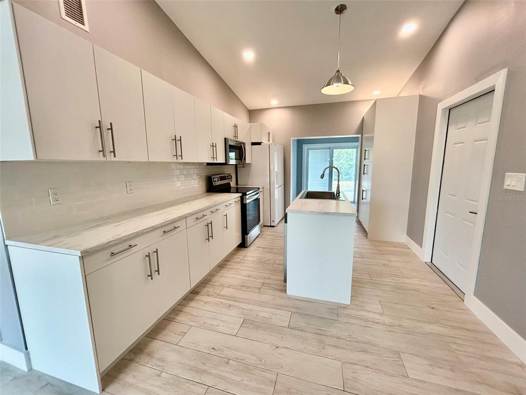 3112 Magnolia Way Punta Gorda, FL 33950 - Photo 4 of 20 a large white kitchen with a sink a refrigerator and a stove